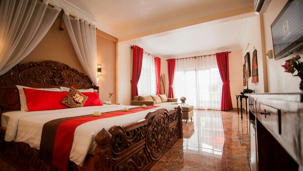A spacious bedroom with a large bed, a sitting area, and a view of the outside. - Reaksmey Chanreas Hotel (Siem Reap)
