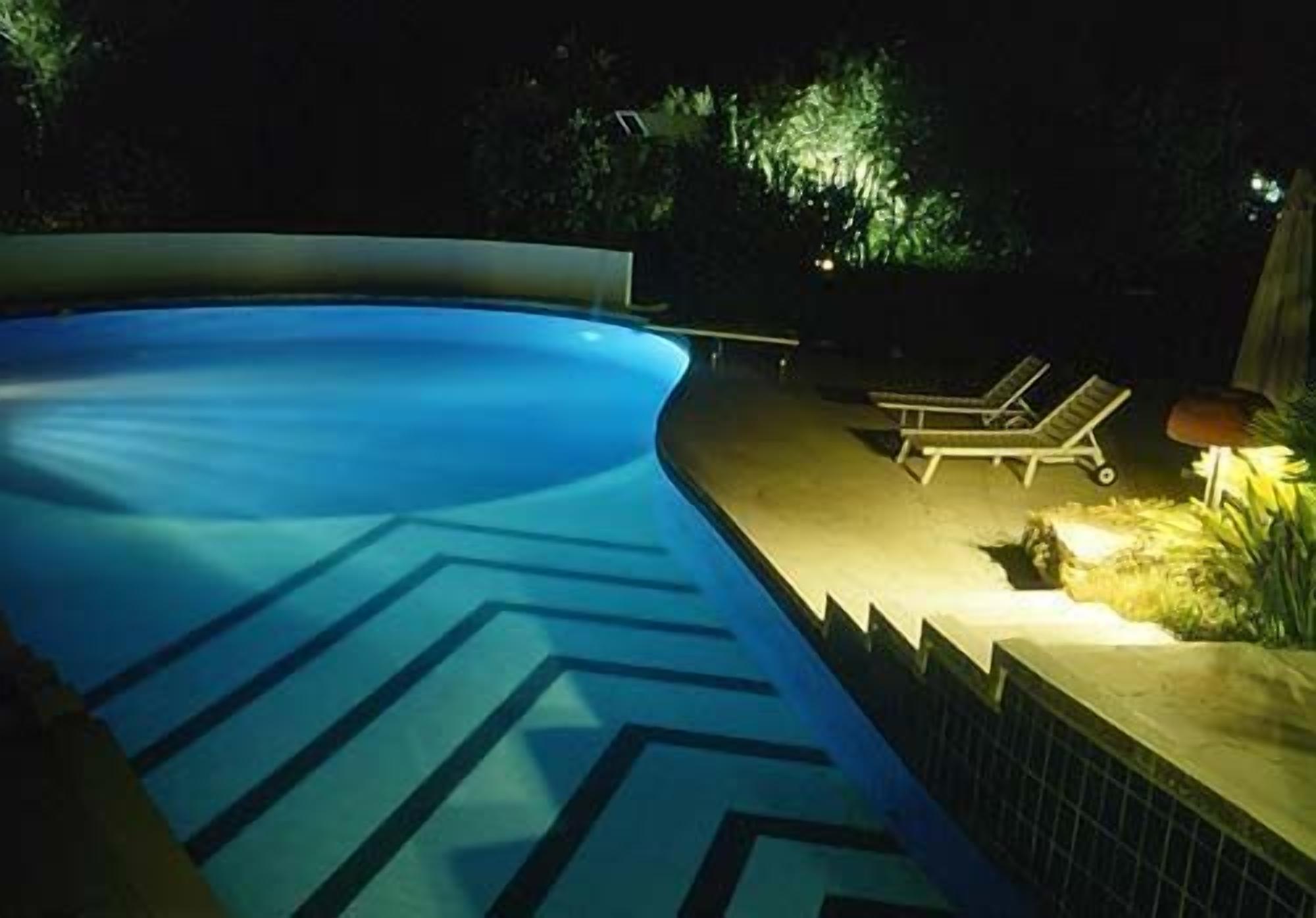 A swimming pool with a geometric pattern on the floor, surrounded by lounge chairs and a low wall.