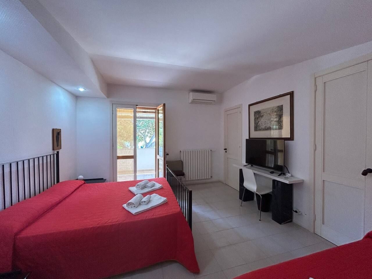 Una habitación con una cama, un escritorio, una silla, un televisor y una puerta.