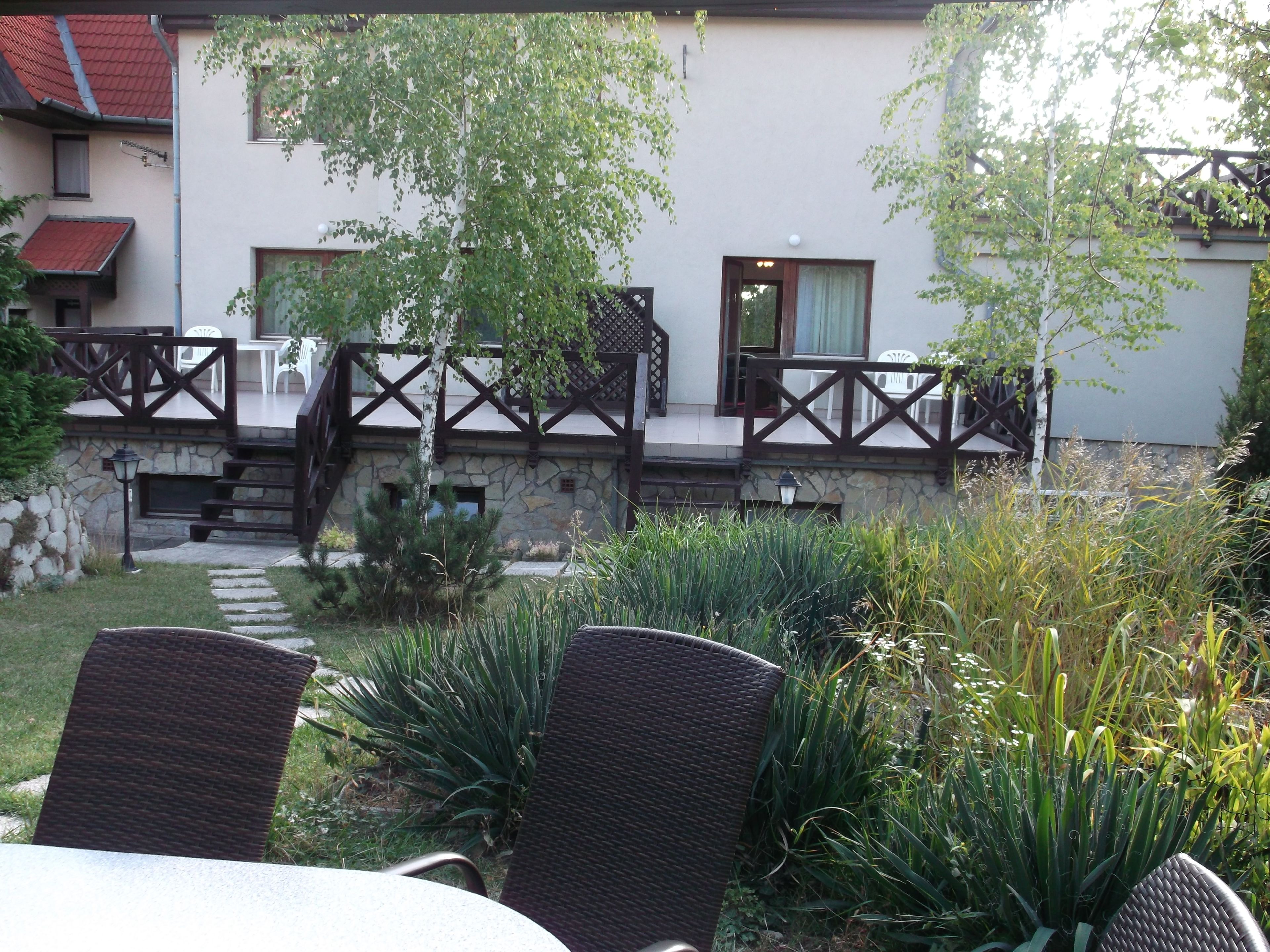 Un patio con mobiliario exterior, un muro de piedra y una terraza de madera con barandillas.