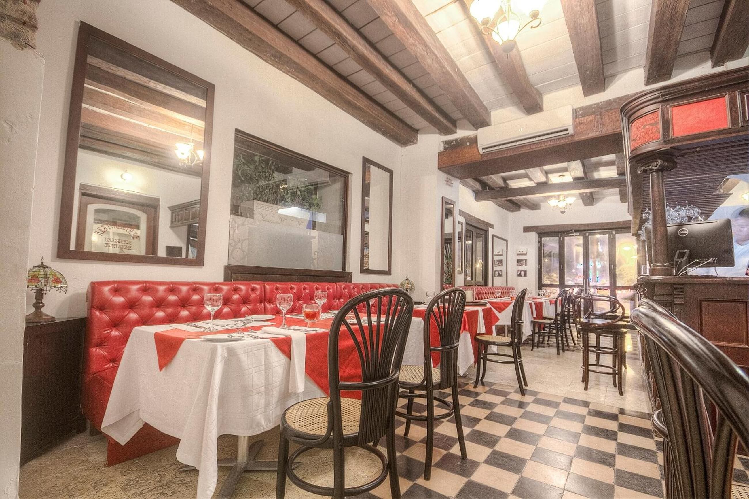 L’intérieur d’un restaurant avec des banquettes rouges, un sol à carreaux et un coin bar.