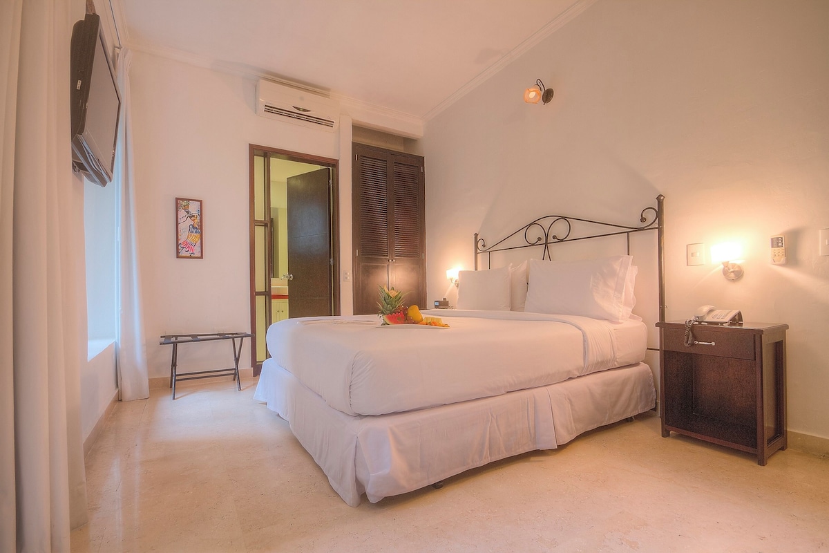 Une chambre à coucher avec un lit, une table de chevet et une petite table de nuit avec un téléphone.