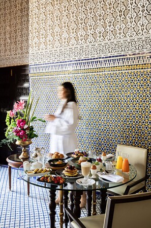 A dining area with a table set for breakfast, including pastries, fruits, and beverages.