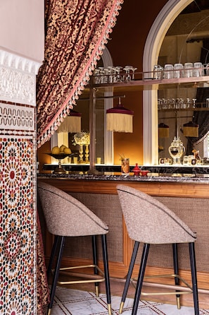 A bar area with two high stools, a mirrored wall, and a patterned curtain.