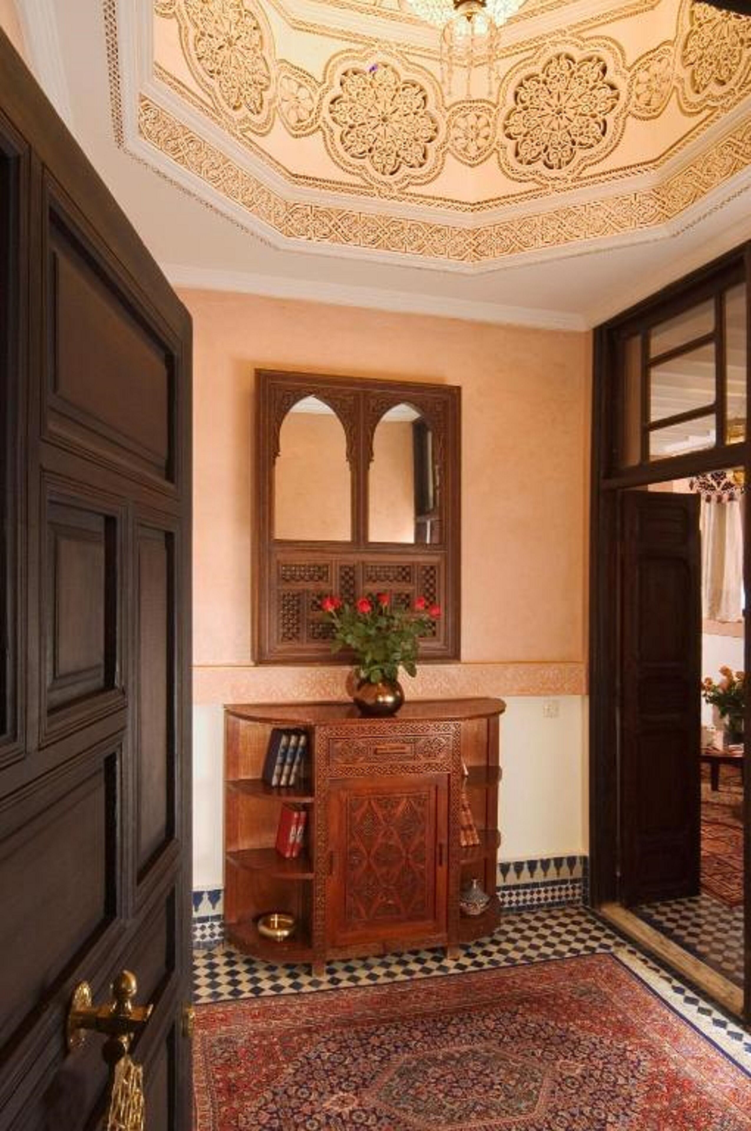 A traditional interior with a wooden cabinet, a mirror, and a patterned rug.