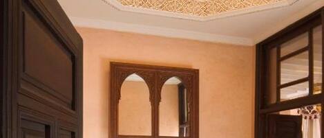 A traditional interior with a wooden cabinet, a mirror, and a patterned rug.