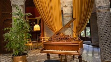 Un piano à queue dans une pièce ornée de colonnes blanches et de rideaux jaunes.