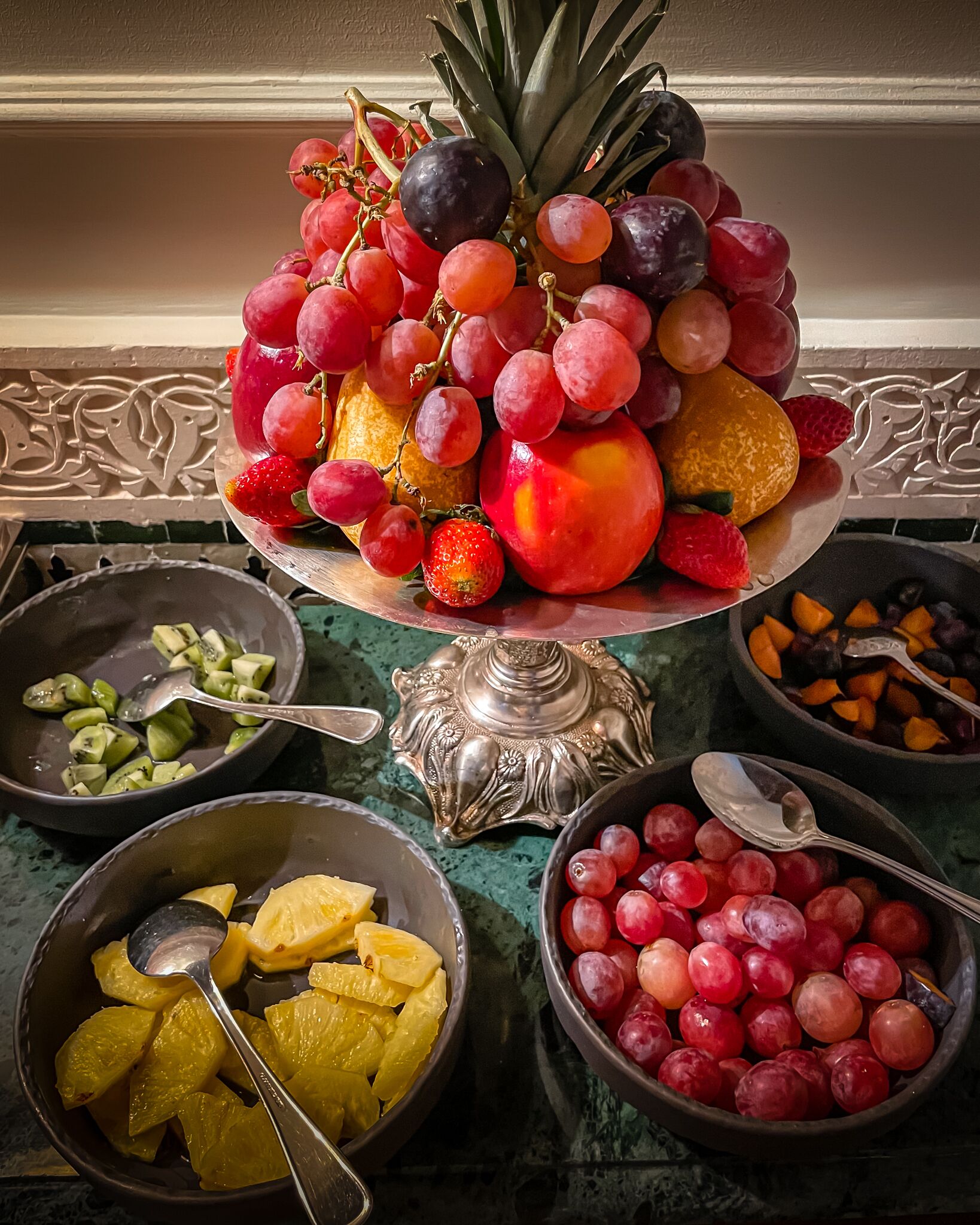 A fruit display with a variety of fruits including grapes, peaches, and strawberries.