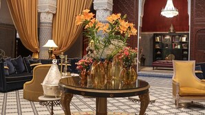 Un intérieur luxueux, agrémenté d’arches richement décorées, d’une table ronde centrale ornée de vases et de sièges confortables.