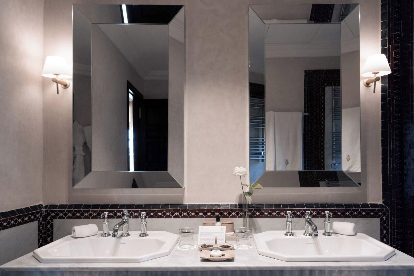 Un baño moderno con dos lavamanos, un espejo grande y un florero decorativo.