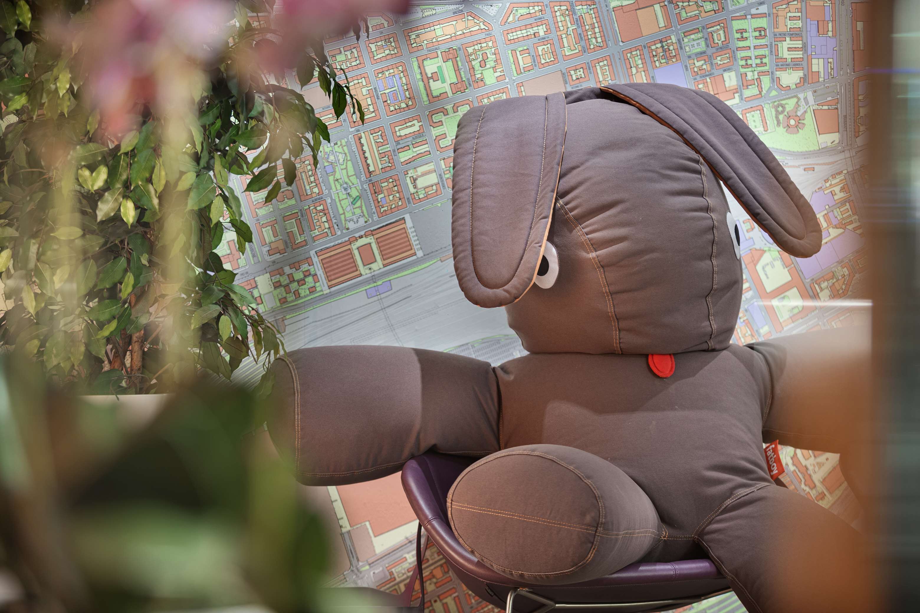 A plush toy chair with a cushion and a red button, set against a backdrop of a detailed map.