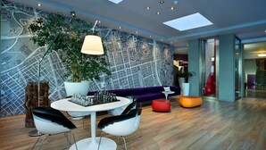 A modern interior with a map mural, a round dining table, two chairs, a sofa, and a potted plant.