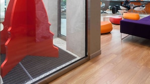 A modern interior with a red abstract sculpture, a glass door leading outside, and a seating area with orange and purple furniture.