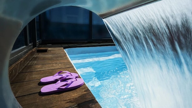 A slide with a wooden deck and a pool with a wave design.