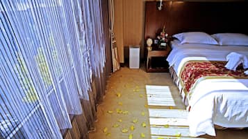 A hotel room with a bed, a nightstand, and a window with curtains.
