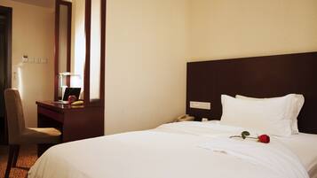 A hotel room with a bed, a desk with a telephone, a chair, and a mirror.