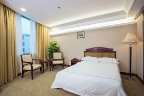 A hotel room with a bed, two chairs, a small table, a lamp, and a plant. - Zhong Hua Hotel (Guangzhou)