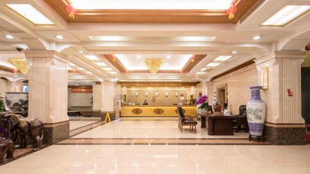 A hotel lobby with a reception desk, a large vase, and a chandelier. - Zhong Hua Hotel (Guangzhou)