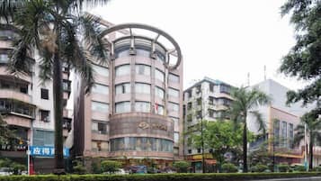A multi-story hotel with a curved facade, surrounded by palm trees and other greenery.