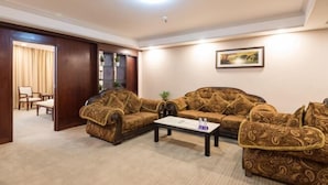 A living room with two patterned sofas, a coffee table, and a framed picture on the wall. - Zhong Hua Hotel (Guangzhou)