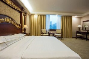 A hotel room with a large bed, two chairs, a desk, and a window with curtains. - Zhong Hua Hotel (Guangzhou)