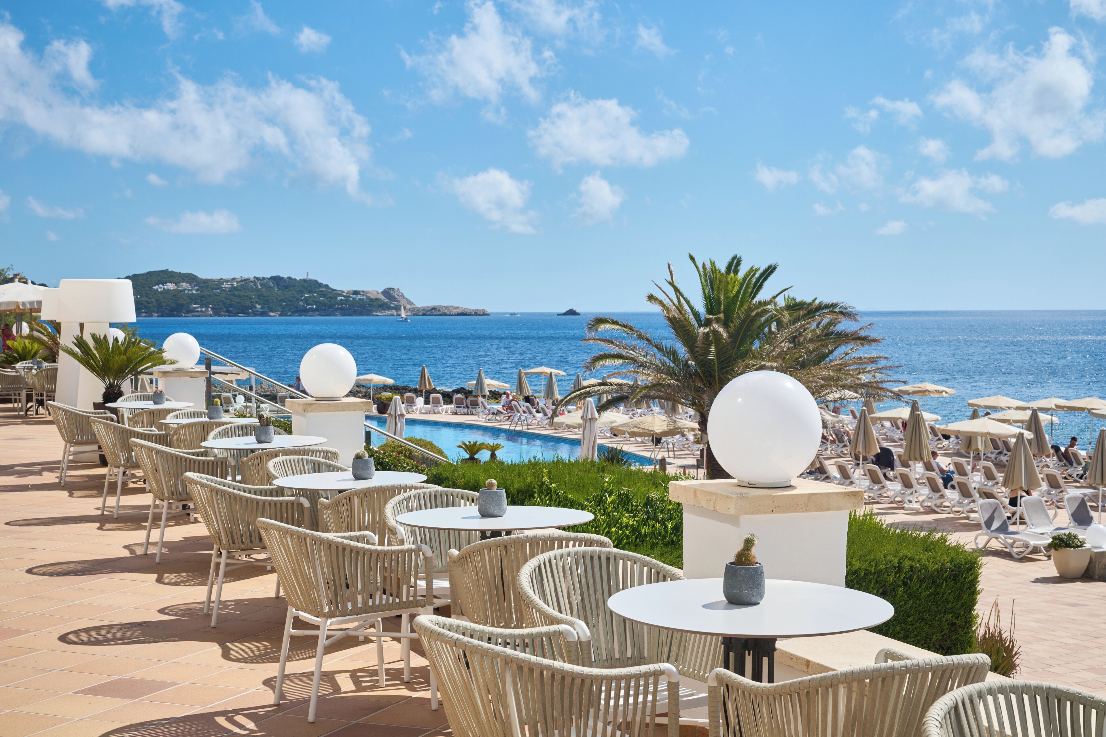 A seaside resort with outdoor seating and a pool.