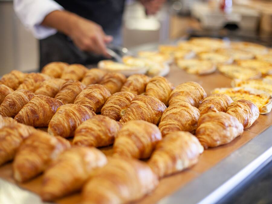 Mostrador de panadería con cruasanes y pizzas.