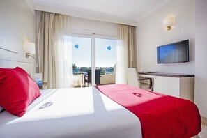 Una habitación de hotel con una cama, un escritorio, un televisor y vistas al exterior.