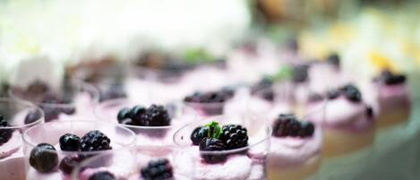 Una fila de copas de postre con una capa cremosa y frambuesas por encima.