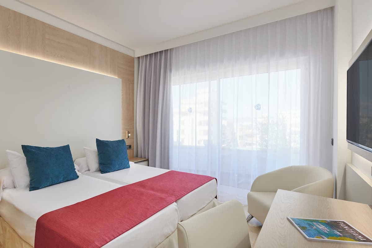 A hotel room with two beds, a desk, and a chair.