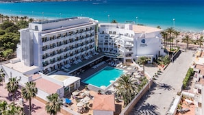 A hotel with multiple balconies, a swimming pool, and a view of the sea.