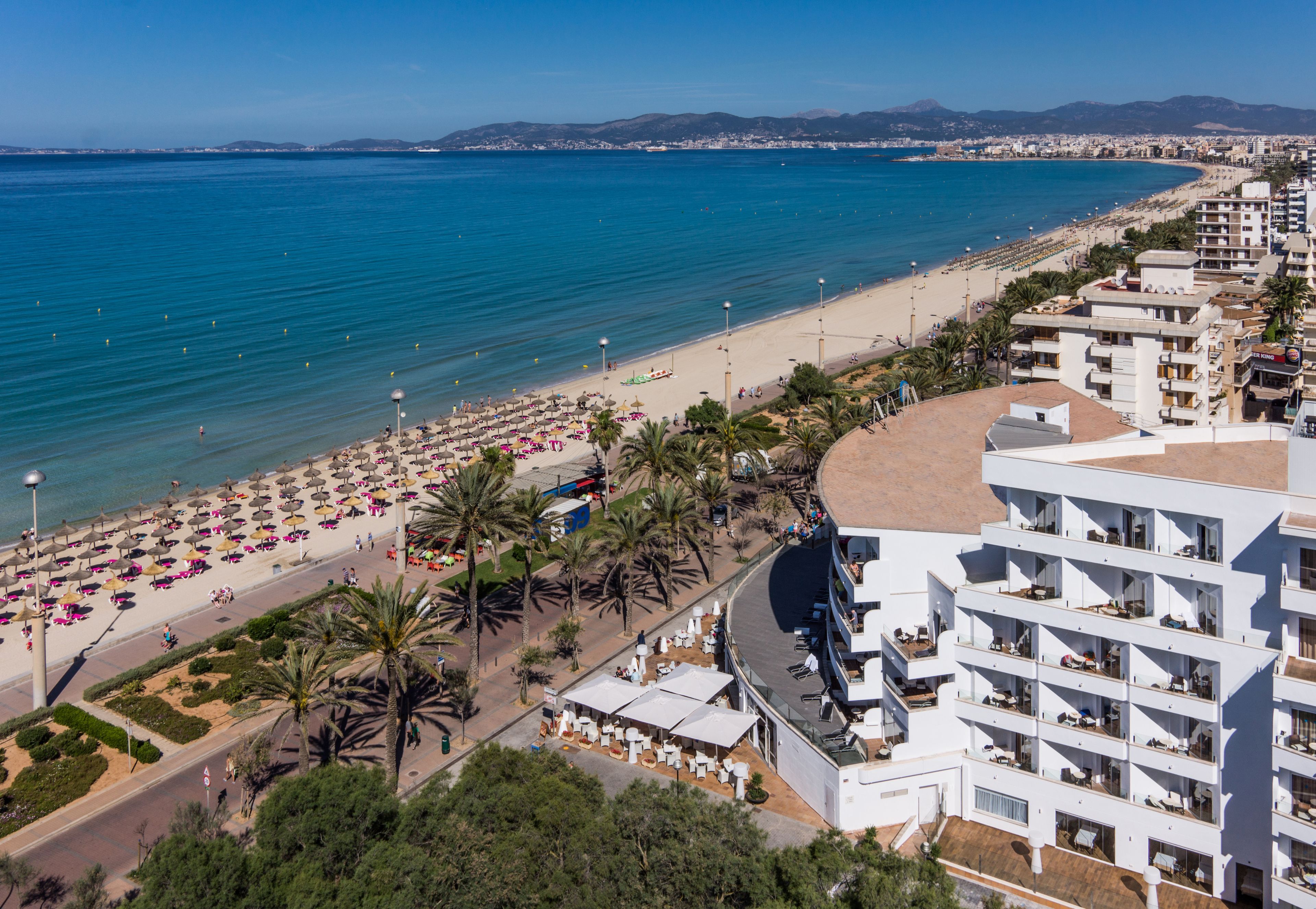 Un hotel costero con varios balcones, ubicación frente a la playa y vistas al mar.