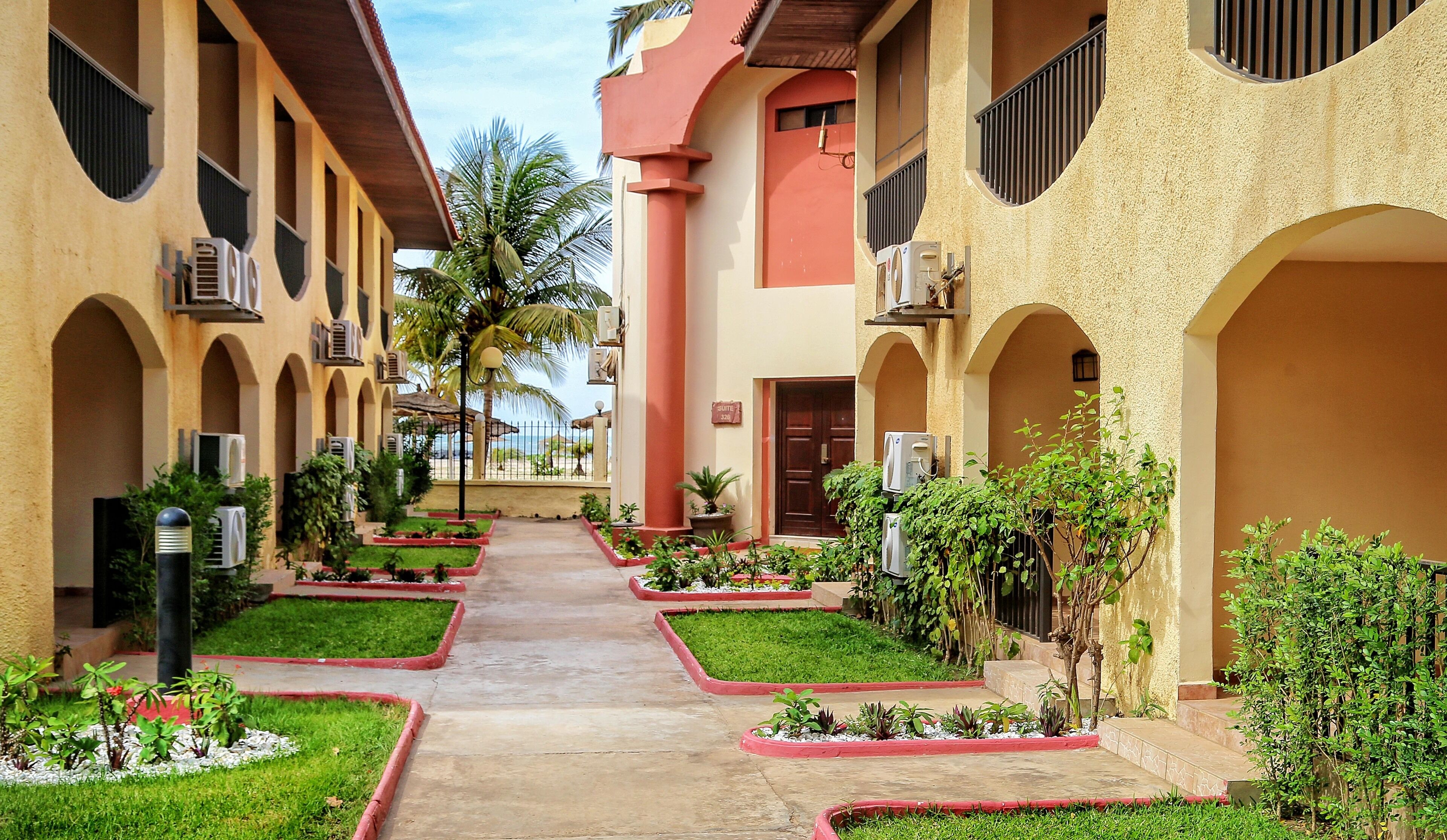 Un pasillo de hotel con varios balcones, unidades de aire acondicionado y plantas en macetas.