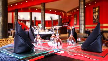 Un restaurante con una mesa dispuesta para dos, con vasos transparentes y servilletas negras.
