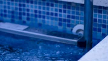 A pool with a tiled edge and a metal handrail.