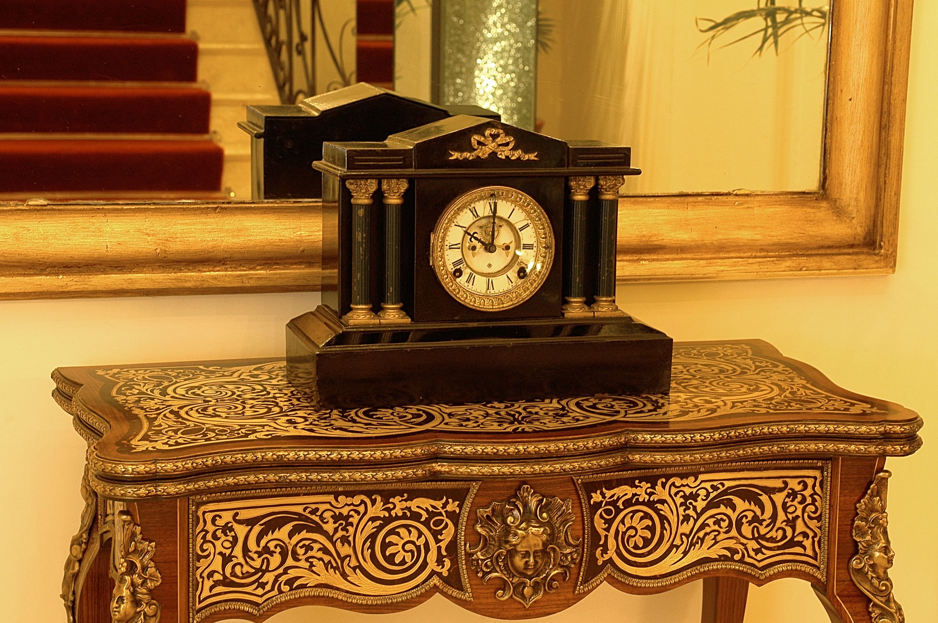 A wooden clock with intricate carvings on a table.