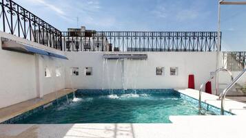 Alberca al aire libre, sombrillas en la alberca y camastros