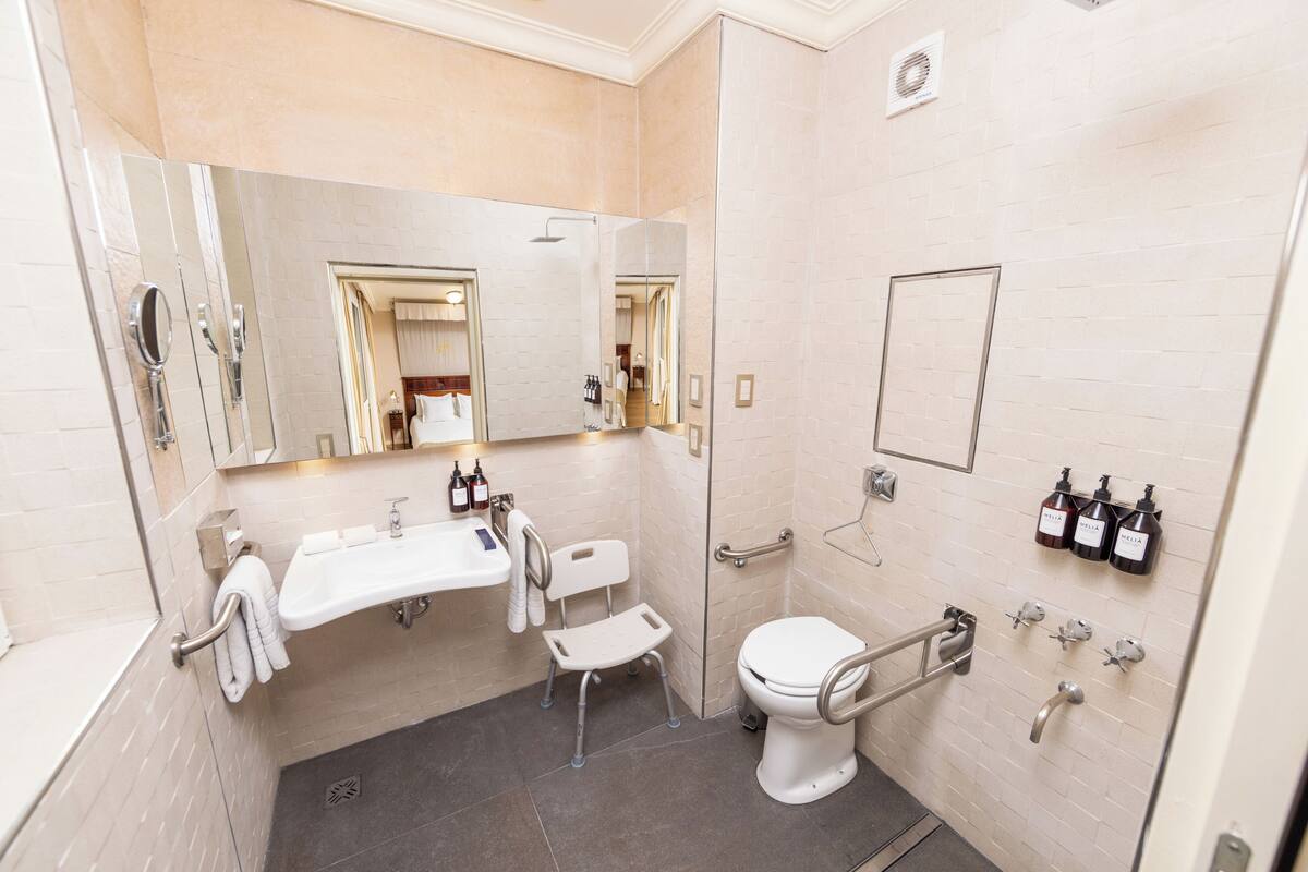 A modern bathroom with a large mirror, a sink, a toilet, and a shower.