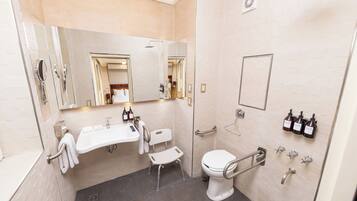 A modern bathroom with a large mirror, a sink, a toilet, and a shower.