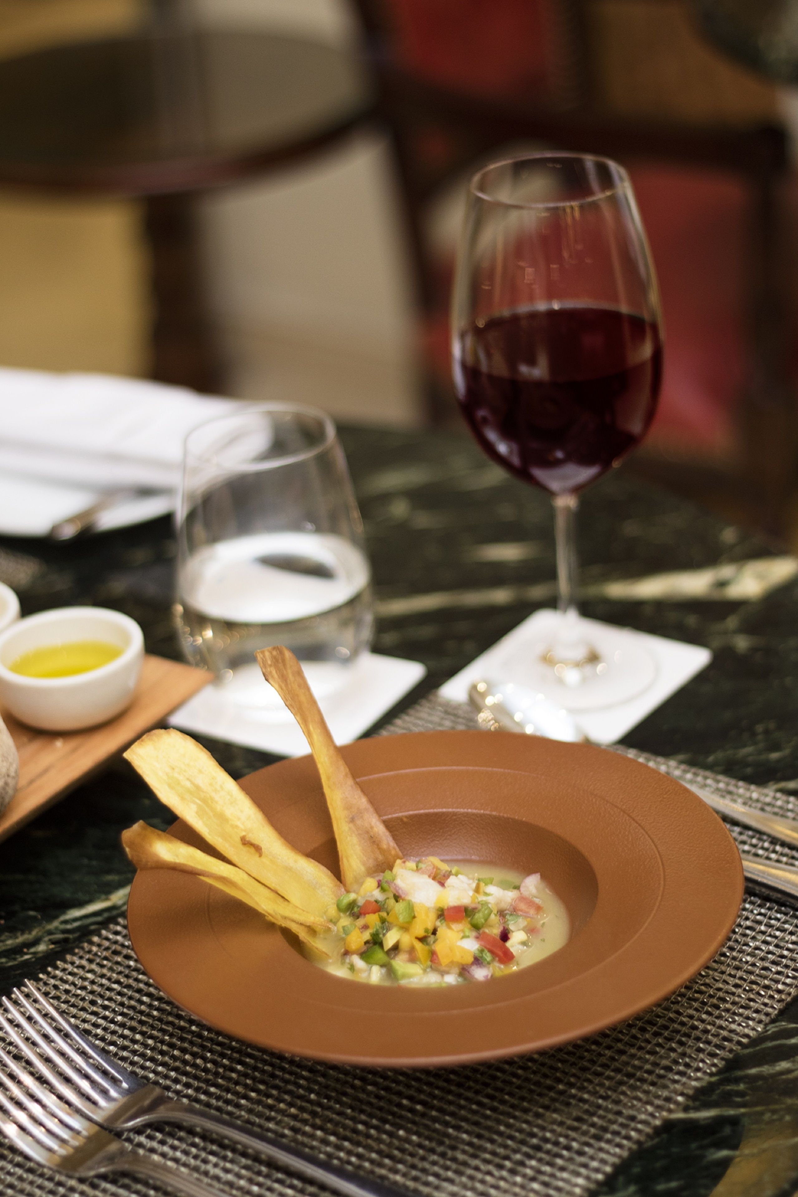 A dining table with a plate of food, a glass of red wine, and a glass of water.