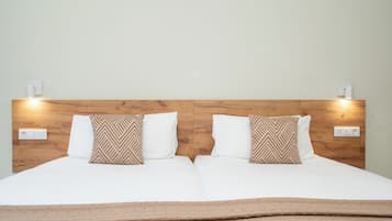 Una cama doble con cabecera de madera, dos almohadas blancas y una manta marrón.