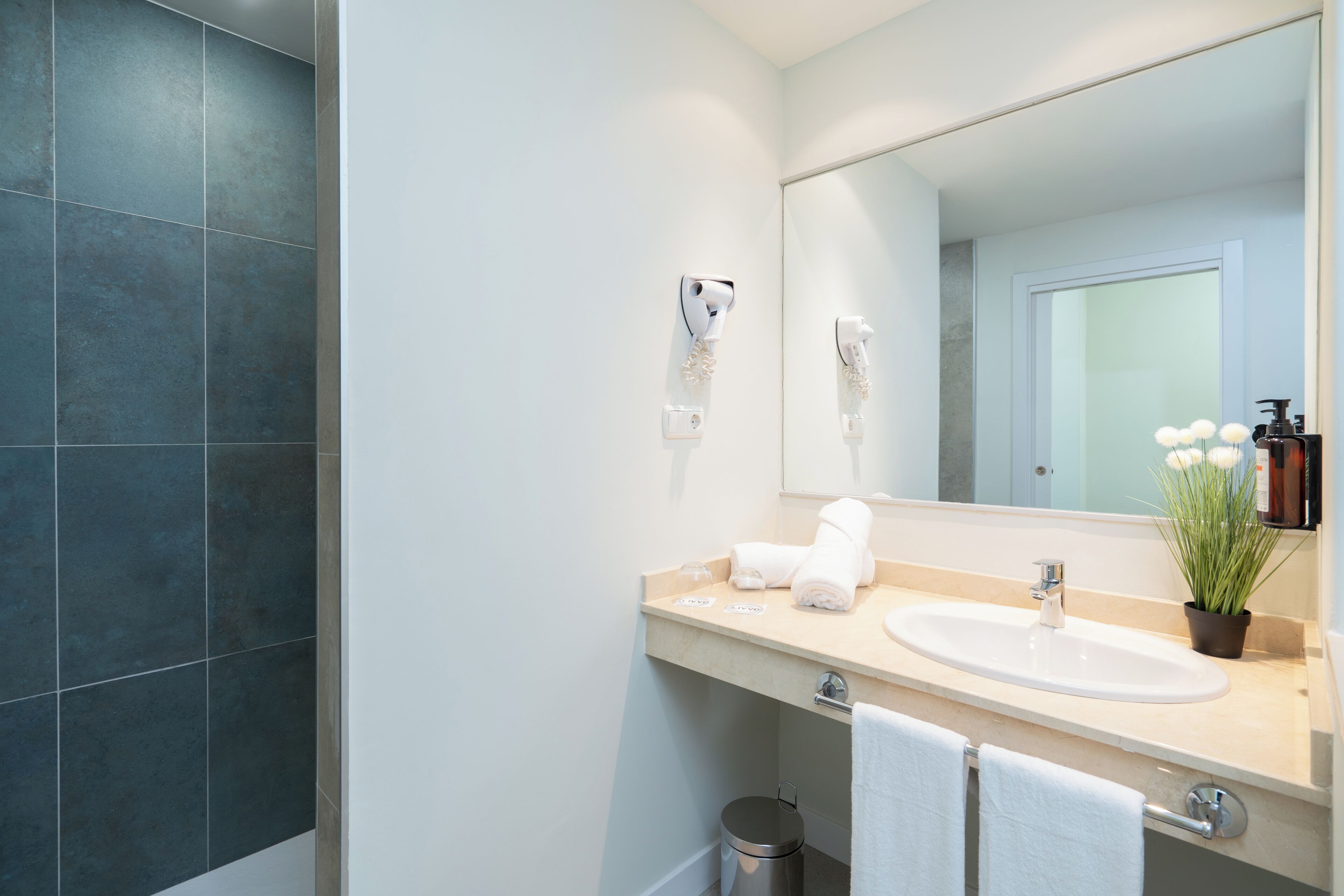 Une salle de bain moderne avec un grand miroir, un lavabo et un porte-serviettes.