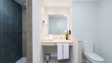 A modern bathroom with a large mirror, a sink, a toilet, and a shower area.