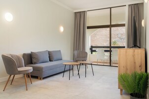 A modern living room with a grey sofa, two armchairs, a coffee table, and a wooden sideboard.