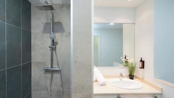 Un baño moderno con ducha, lavamanos y espejo.