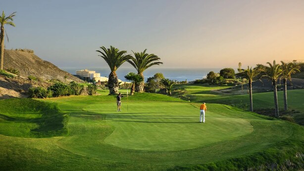 Un campo de golf con vista al océano y un edificio al fondo.