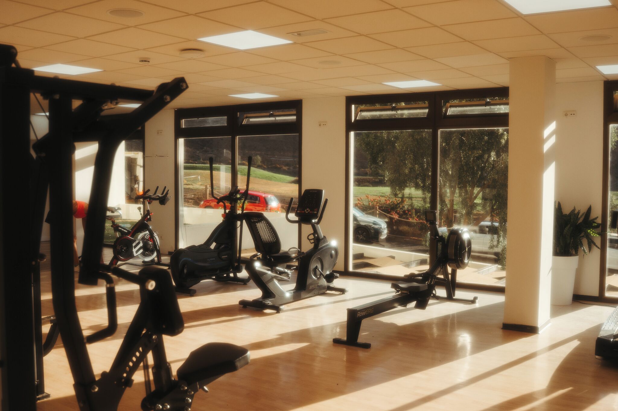 A gym with exercise equipment, large windows, and a view of the outdoors.