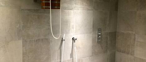 Un espace douche équipé d’un seau en bois, de deux pommes de douche et d’un panneau de commande fixé au mur.