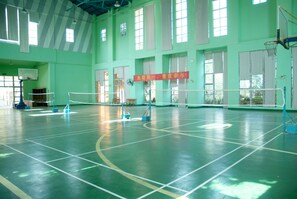 A large indoor sports hall with a basketball court, multiple windows, and a red banner. - Hawana Resort Hotel (Guangzhou)