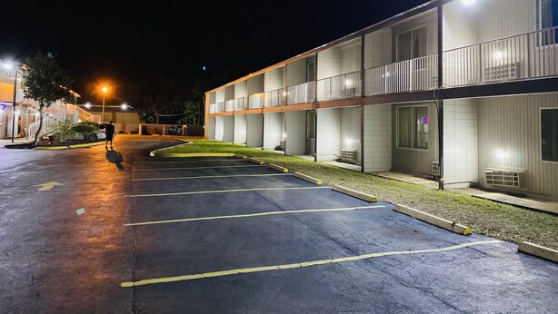 Un motel de varios pisos con estacionamiento, asientos al aire libre y una fachada bien iluminada.